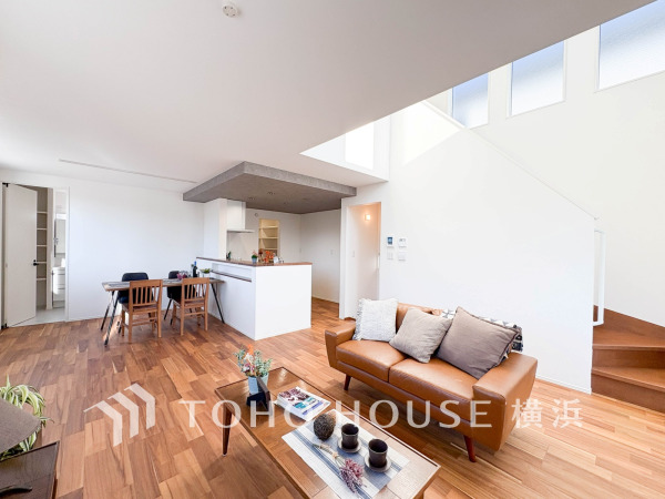 開放感あふれる吹き抜けと無垢床が魅力のリビング。自然光がたっぷり入り、温かみのある空間です。