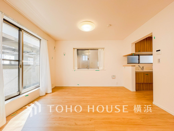 明るい光が差し込む広々としたリビング。木目調の床と白壁が温かみのある空間を演出しています。