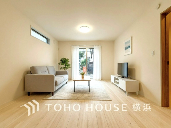 明るい自然光が差し込む、シンプルで落ち着いたリビングルーム。快適な寛ぎ空間を実現しています。（家具・装飾品等はAI加工です）