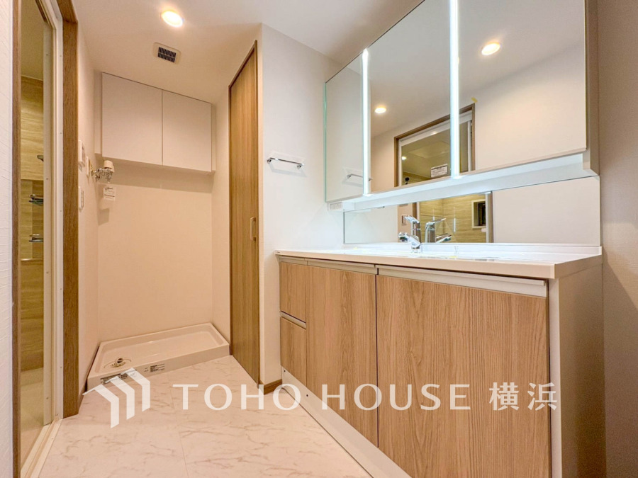 木目調の収納と大きな鏡を備えた清潔感ある洗面スペース。使いやすさと収納力を両立しています。