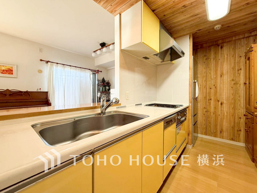 温かみのある木目とイエローの扉が特徴の明るいキッチン。リビングと繋がり家族の会話も弾みます。