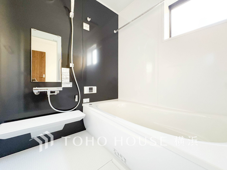 シックな黒壁と白を基調とした清潔感あふれる浴室。窓から自然光が入り、リラックスできる空間です。