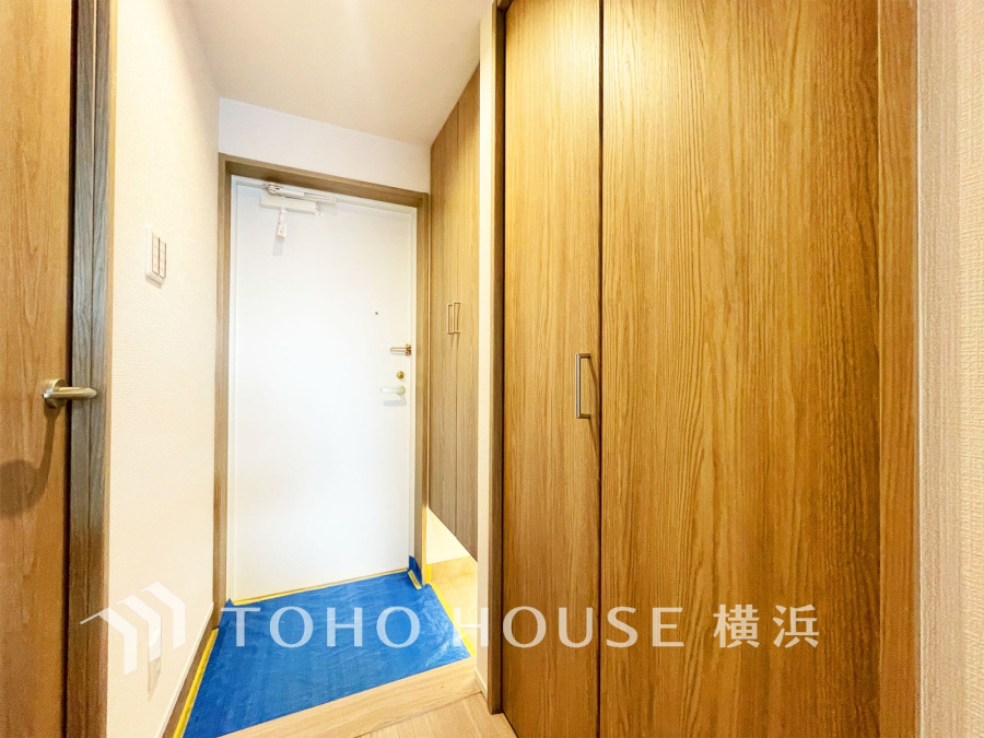 木目調の収納が充実した明るい玄関。清潔感のある白いドアが印象的な、使い勝手の良いスペースです。