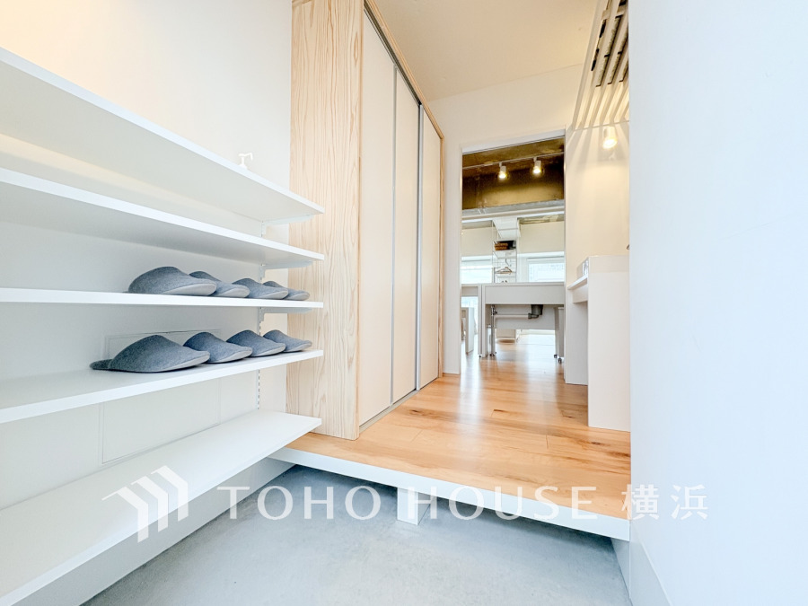 白色を基調とした清潔感溢れる玄関空間。オープンシェルフとトールサイズの収納付きです。