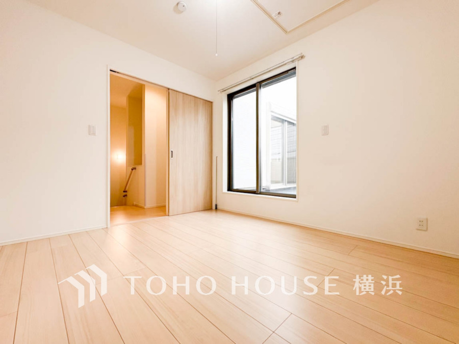 明るい自然光が差し込むシンプルな洋室。木目調の床と建具で温かみのある空間です。