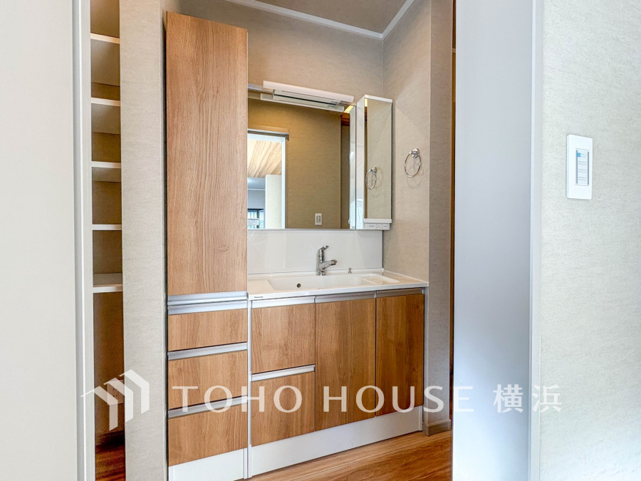 木目調の扉が温かみを演出する洗面台。収納豊富で使い勝手の良いスペースが魅力です。