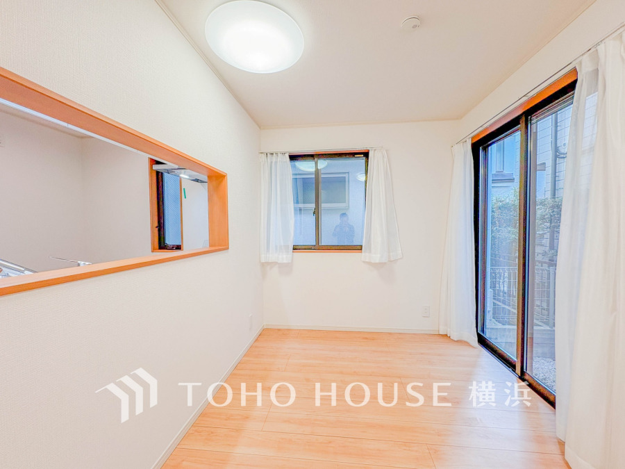 大きな窓から自然光が差し込む明るい洋室。キッチンとつながる開放的な間取りで快適な生活空間を実現。