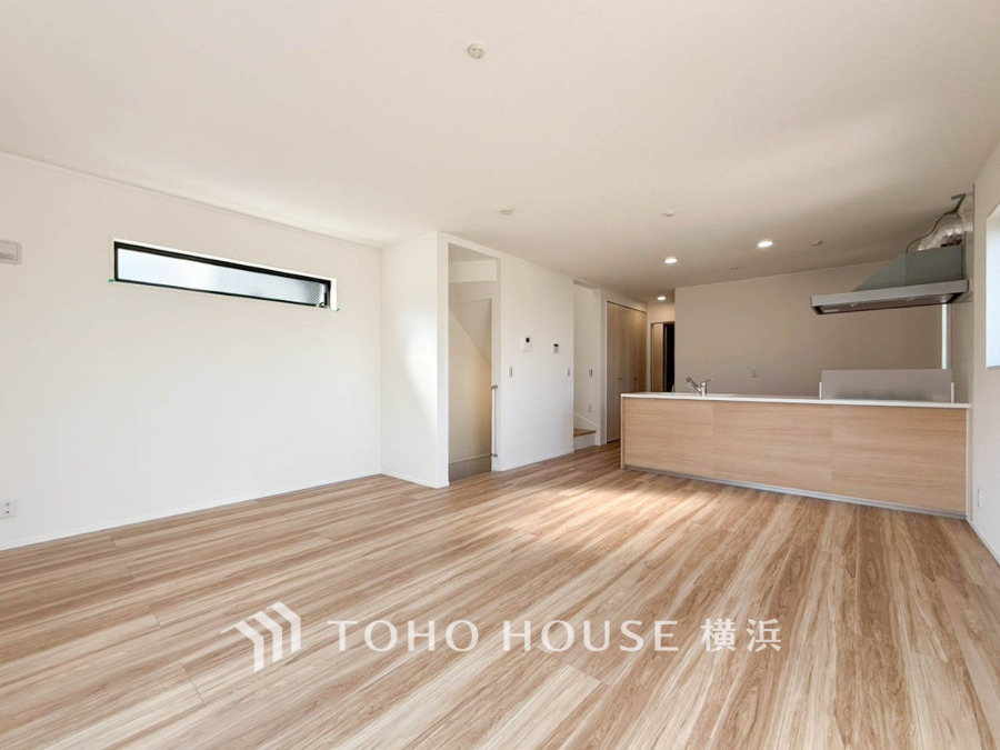 明るい光が差し込む、ナチュラルな木目床の広々としたリビング・ダイニングキッチン空間です。