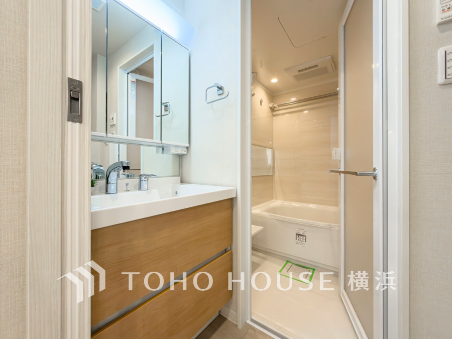 木目調収納付きの洗面台と清潔感あるユニットバスを備えた、使い勝手の良いバスルーム空間です。