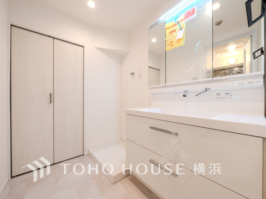 清潔感あふれるホワイト基調の洗面室。大容量収納と洗濯機置き場が使いやすく配置されています。