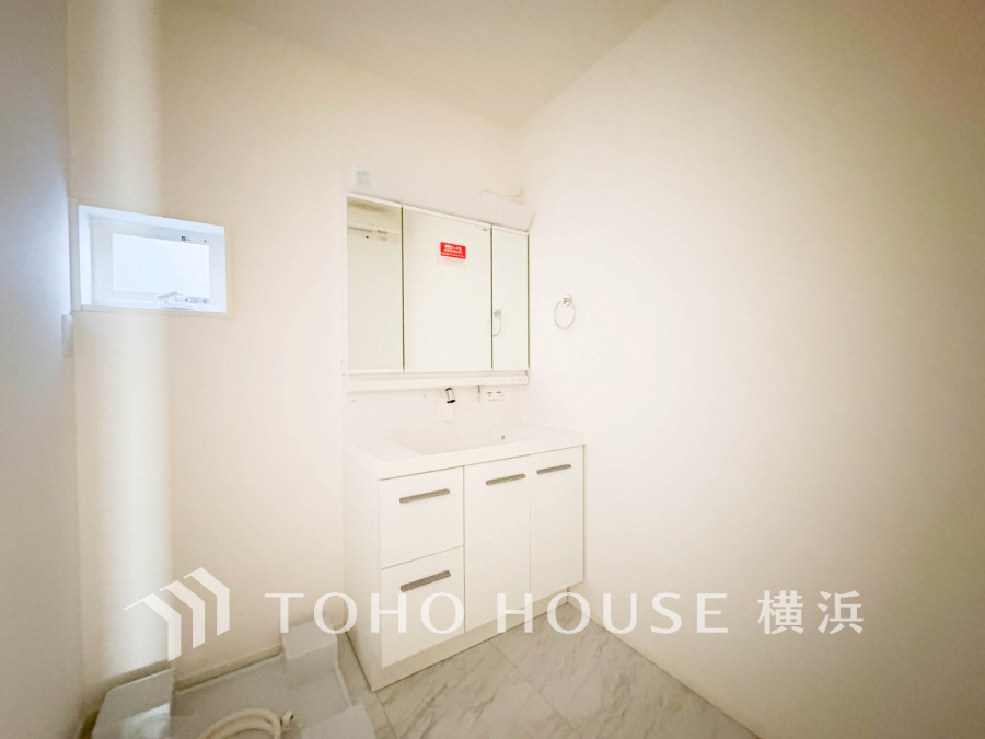 シンプルで清潔感あふれる洗面台と収納を備えた、明るく広々とした洗面スペースです。