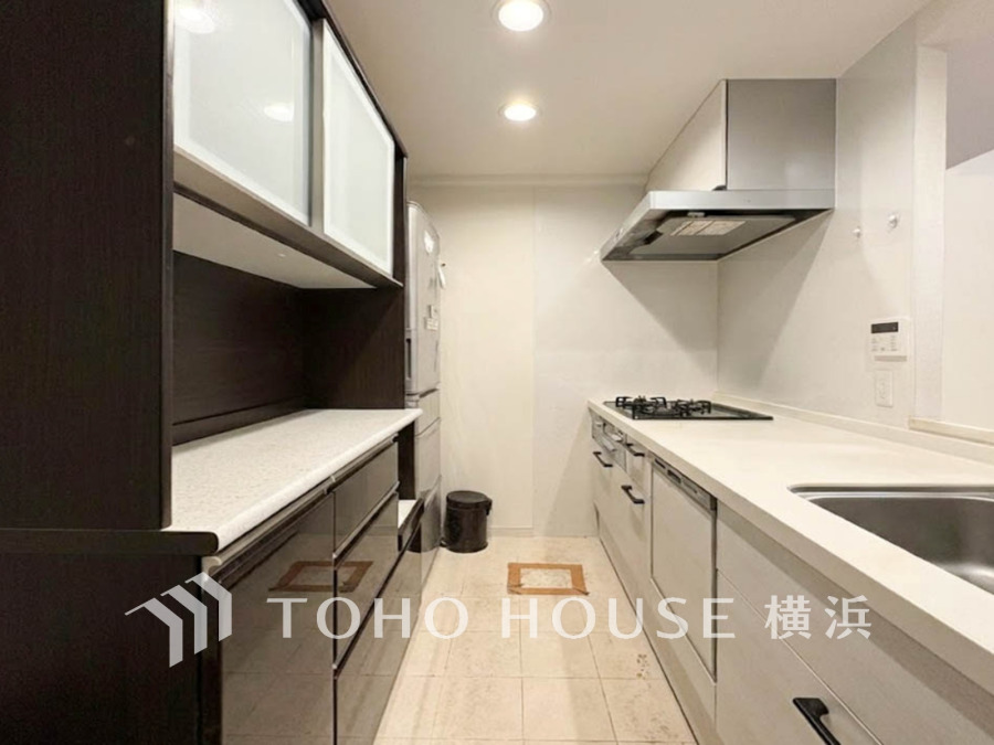 収納豊富で機能的なシステムキッチン。清潔感ある白とダークカラーのコントラストが美しい空間です。