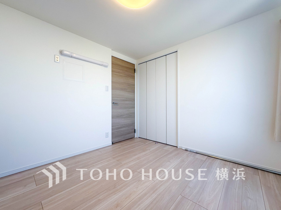 ナチュラルな木目調の床と白い壁が調和する明るい洋室。収納スペースも充実し使い勝手良好です。