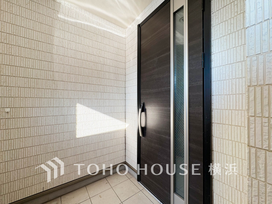 清潔感あふれるタイル張りの玄関スペース。大きなドアで開放感と安心感を両立しています。