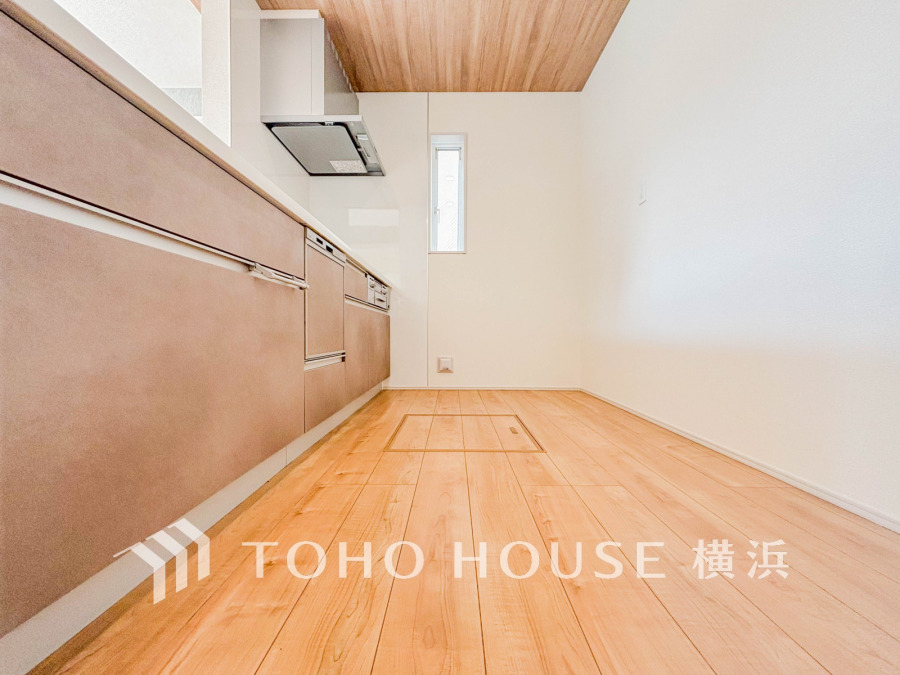 木目調の天井と床が温かみを演出する、機能的で広々としたキッチン空間です。