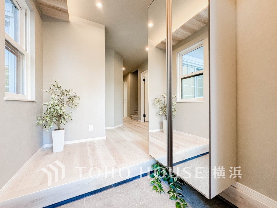 大型ミラー付きのシューズボックスを設置した明るい玄関スペース。