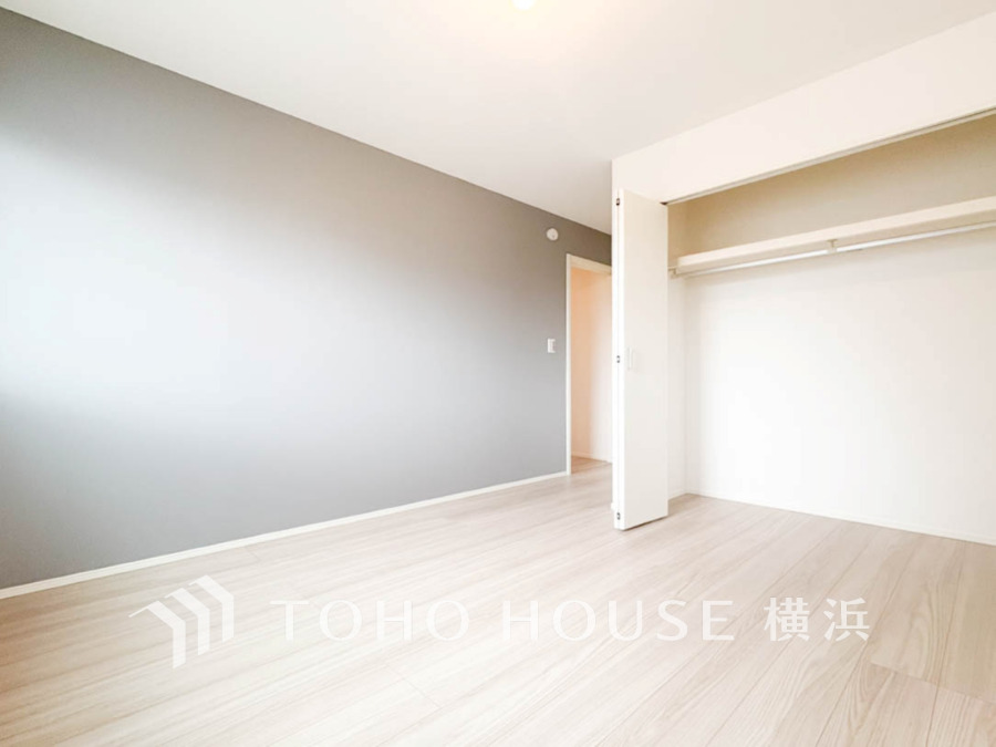 シンプルで落ち着いたグレーのアクセントクロスと広々とした収納スペースが魅力の明るい洋室です。