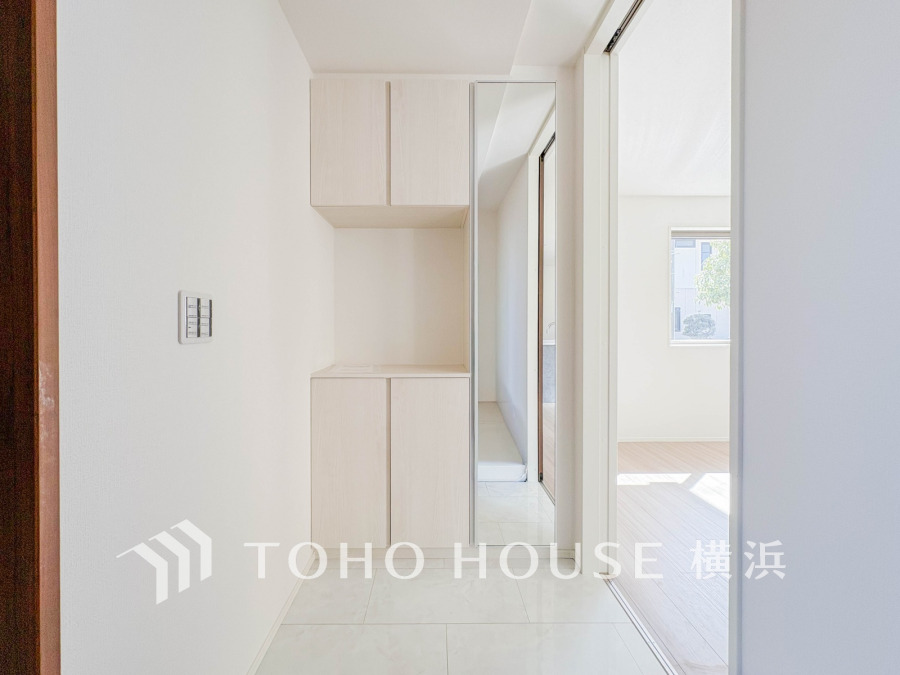 明るく清潔感のある玄関。大容量の収納と姿見ミラーで実用性と便利さを兼ね備えています。