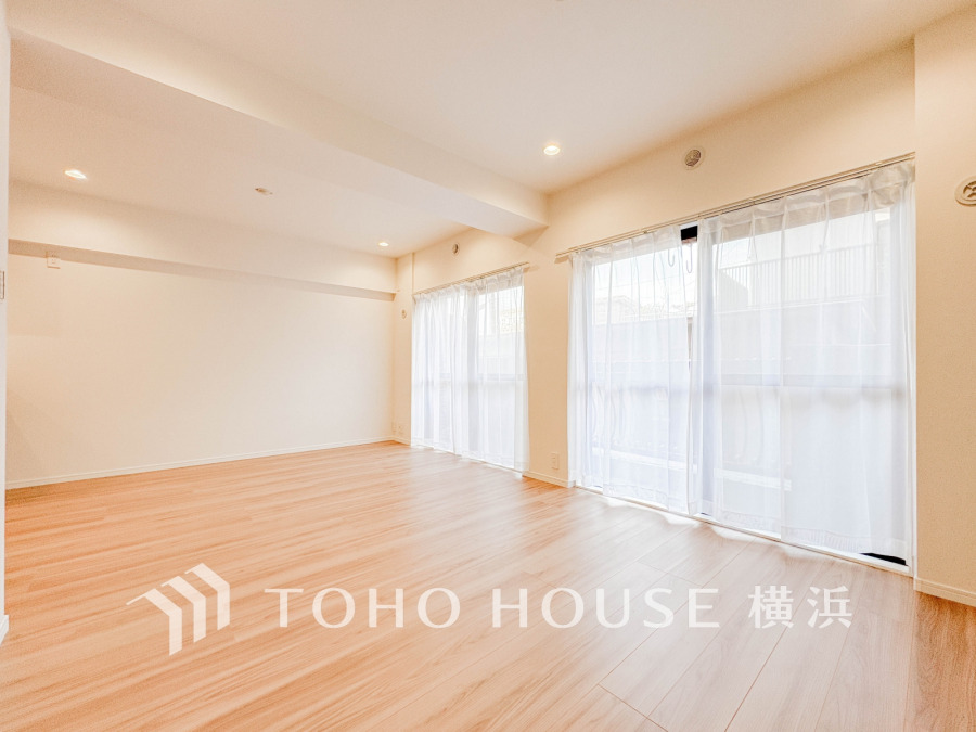 明るい自然光が差し込む広々としたリビング。ナチュラルな木目の床が温かみを演出します。