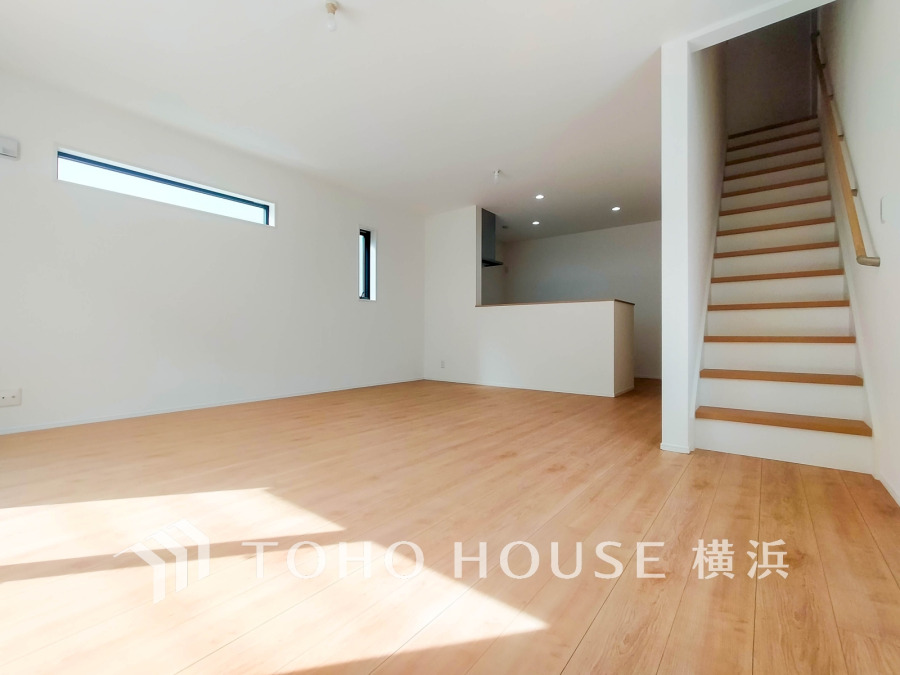明るい光が差し込む広々リビング。シンプルな内装とキッチン横の階段が使いやすさを演出します。