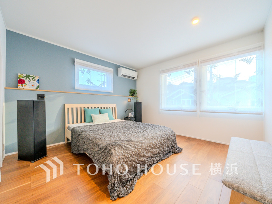 柔らかな光が差し込む、落ち着いたブルーのアクセント壁が魅力の快適な寝室空間です。