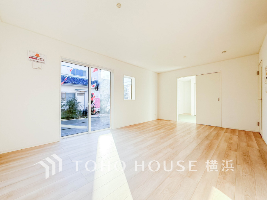 明るい自然光が差し込む、広々としたリビング。シンプルな白壁と木目調フローリングで温かみのある空間です。