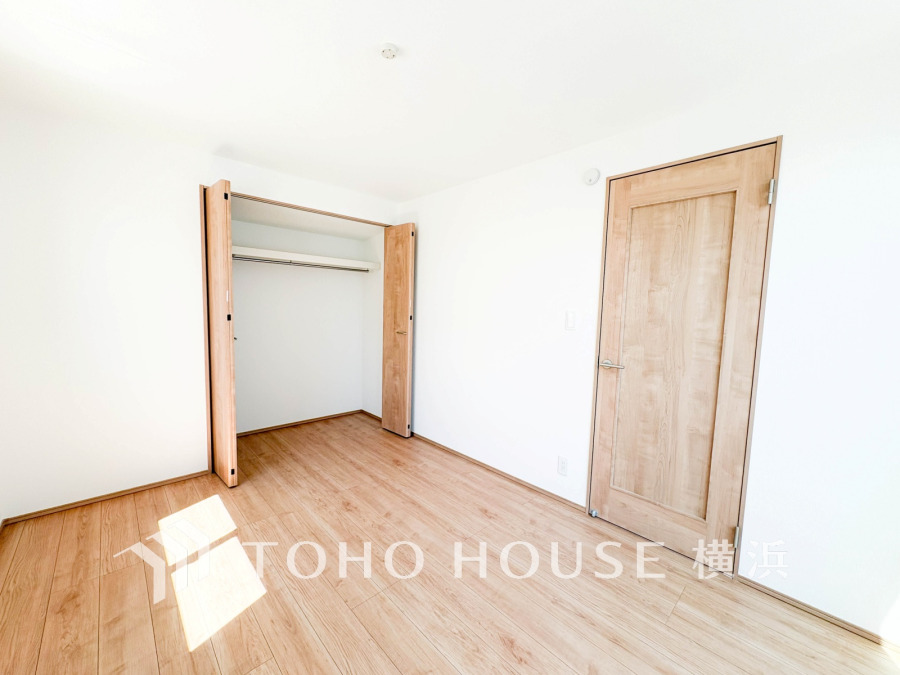 明るい自然光が差し込む、木目調の床と建具が温かみを感じさせるシンプルな洋室です。収納も充実しています。