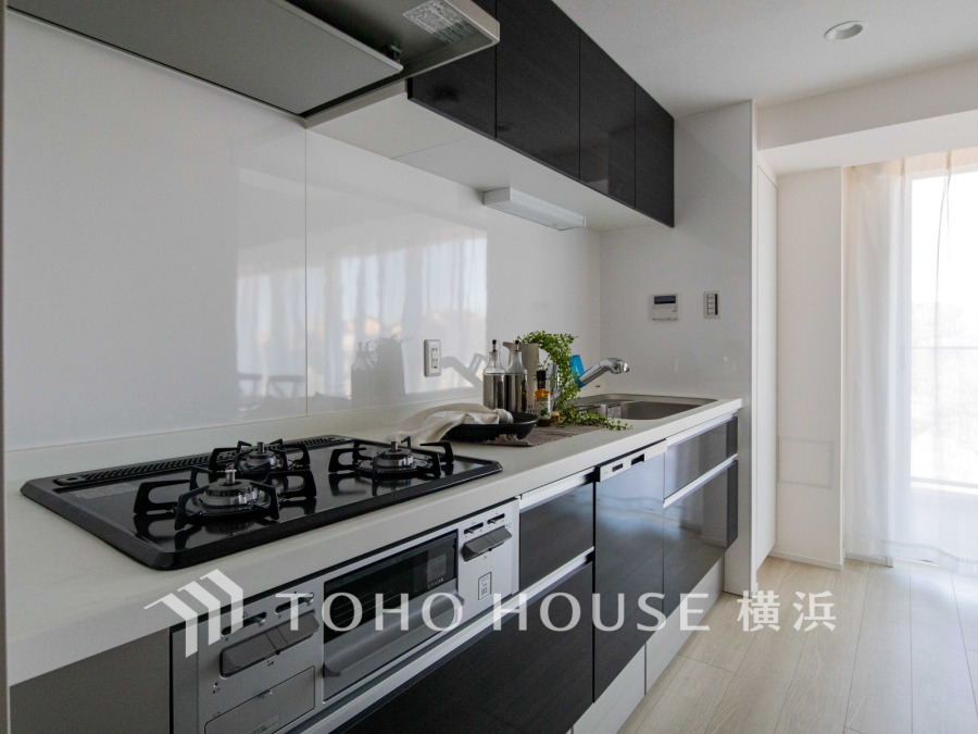 スタイリッシュな黒のキャビネットと白を基調とした清潔感あふれるキッチン。自然光が差し込む明るい空間です。