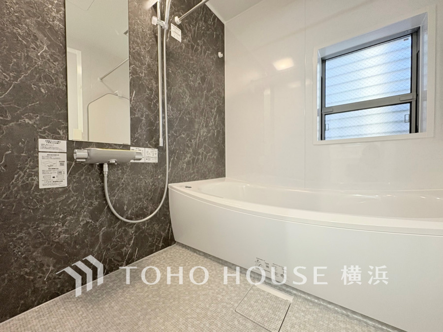 スタイリッシュなブラックのアクセント壁と清潔感あるホワイトバスルームが調和した快適な浴室空間です。