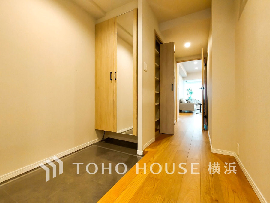 広々とした玄関スペースにはミラー付きの収納棚を完備し、明るく開放的な廊下がリビングへと続きます。