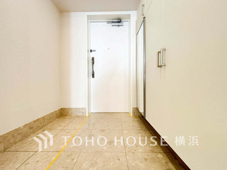 清潔感あふれる玄関は、大理石調のタイルが高級感を演出し、収納スペースも充実しています。