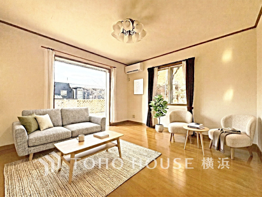 大きな窓から自然光が差し込む明るいリビング。ウッドデッキに繋がり開放感のある空間です。（装飾品はAI加工です）