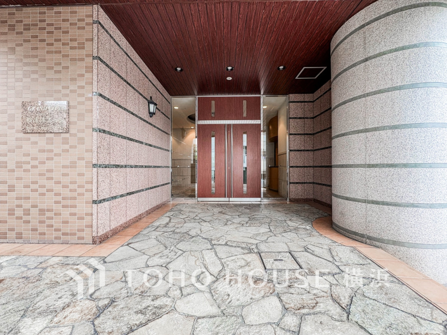 上質な石貼りのアプローチと木目天井が調和する、落ち着きあるマンションのエントランスです。