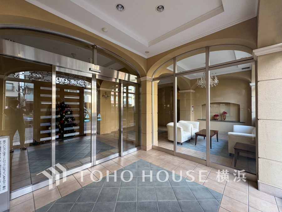 エレガントなアーチ型天井とガラス張りのエントランスが特徴の、落ち着いた雰囲気のマンションロビーです。