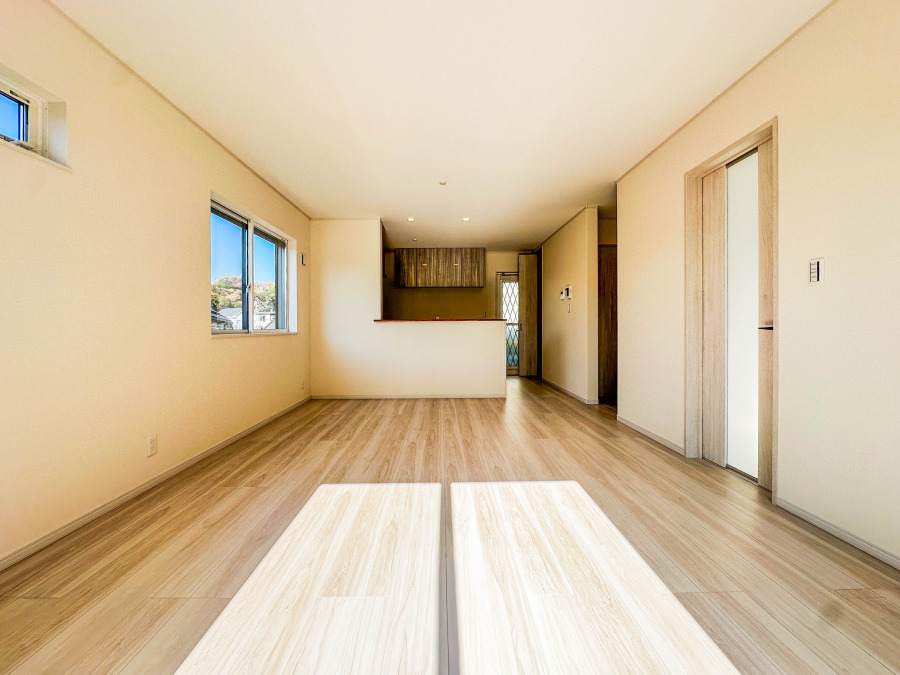 明るい自然光が差し込む、木目調の床が温かみを感じさせる広々としたリビングダイニング空間です。