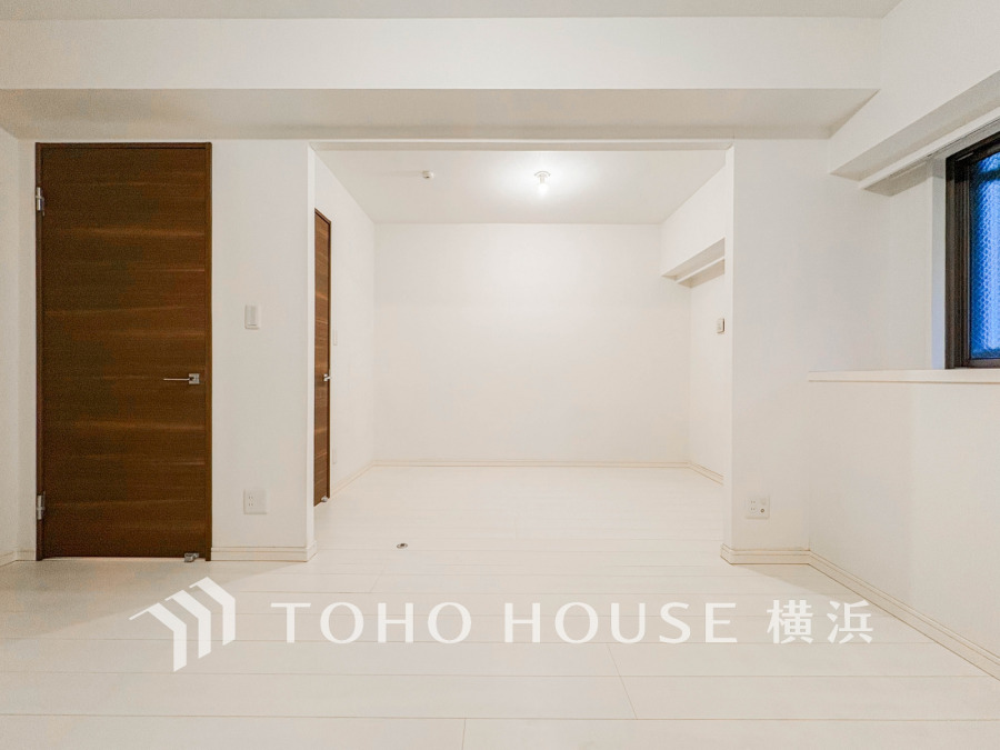 白を基調とした明るく清潔感のある室内。木目調の扉が温かみを添えるシンプルな空間です。