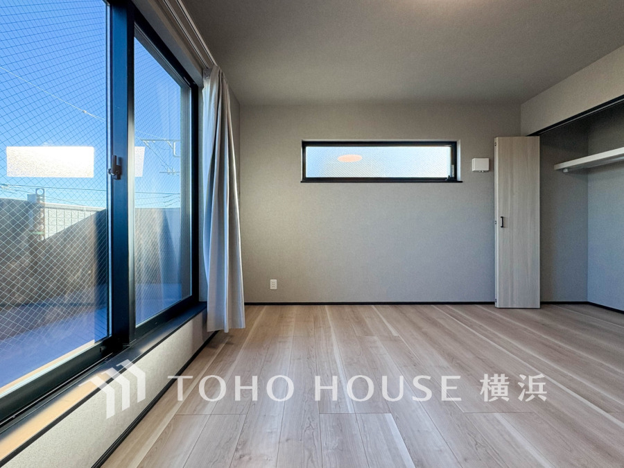 大きな窓から光が差し込む明るい洋室。広々とした収納スペースも備えた快適な空間です。