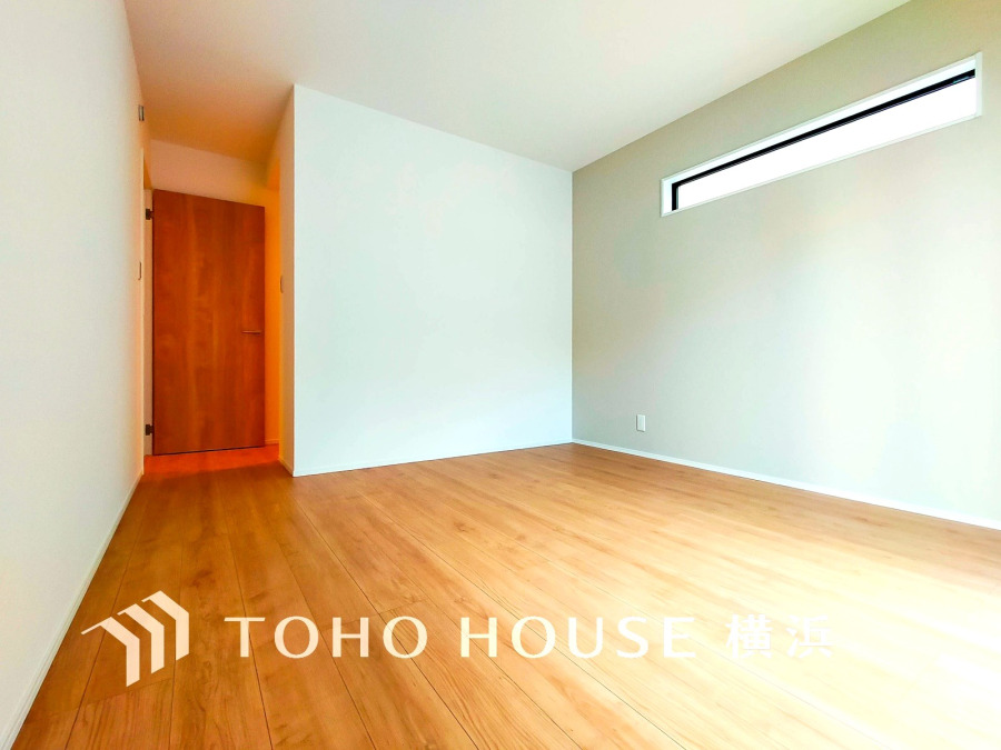 シンプルで明るい空間が広がる洋室。横長窓から自然光が差し込み、快適な居住空間を演出します。