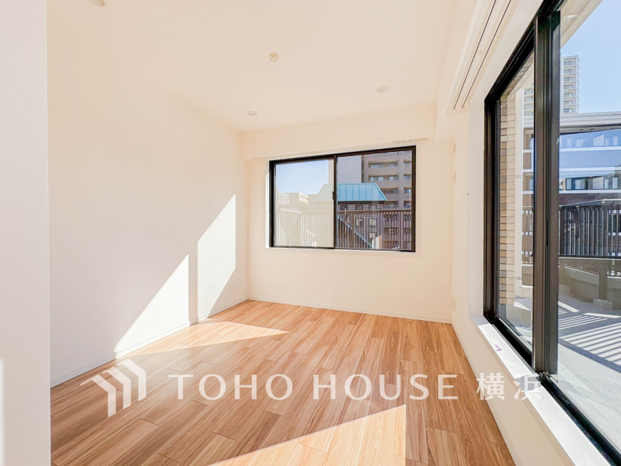 大きな窓から自然光がたっぷり入り込む明るい洋室。清潔感ある白壁と木目調フローリングが調和した空間です。