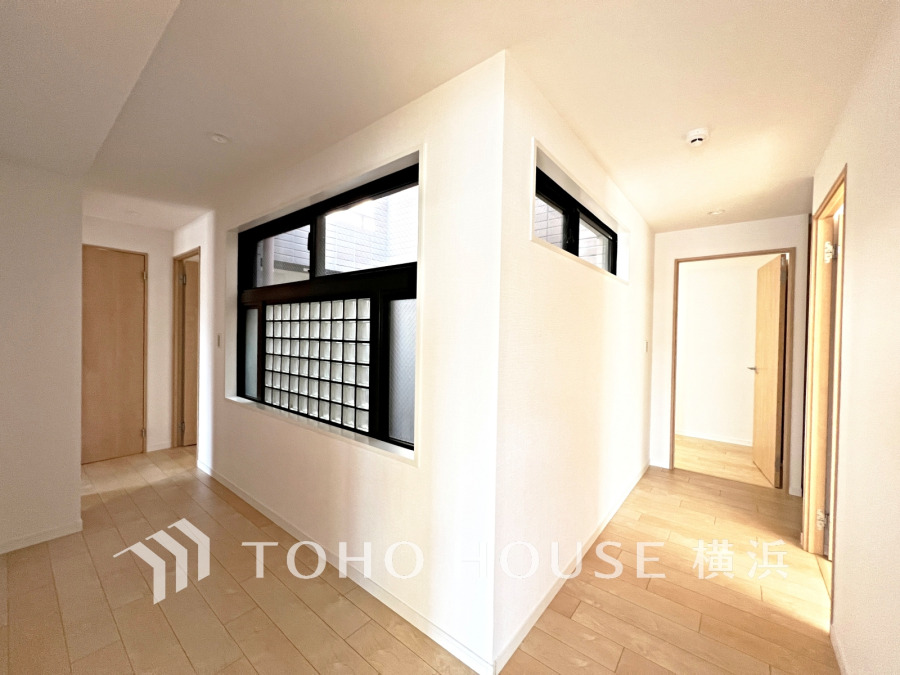 マンション内の吹抜けから室内に自然光が差し込む明るい廊下。ガラスブロックのお洒落な空間です。