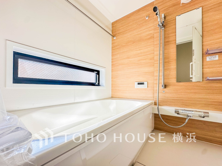 木目調の壁が温かみを演出する、明るく清潔感あふれるバスルーム。窓から自然光がたっぷり入ります。