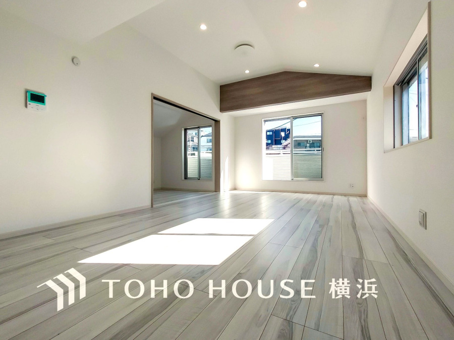 明るい自然光が差し込む広々としたリビング。モダンな木目天井がアクセントの快適空間です。