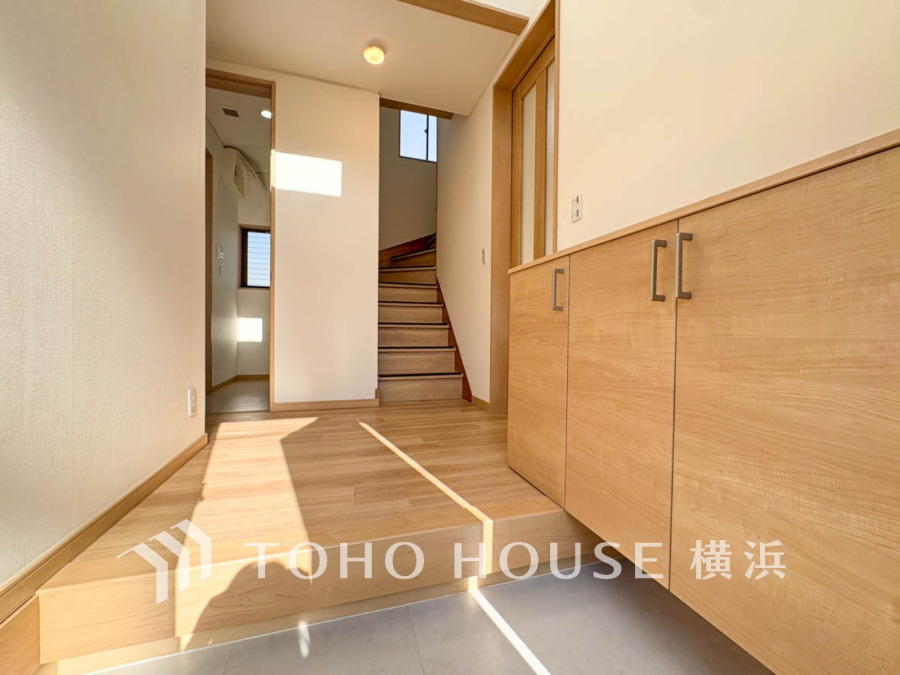 明るい光が差し込む玄関は、収納豊富なシューズボックスと木目調の温かみあるデザインが魅力です。