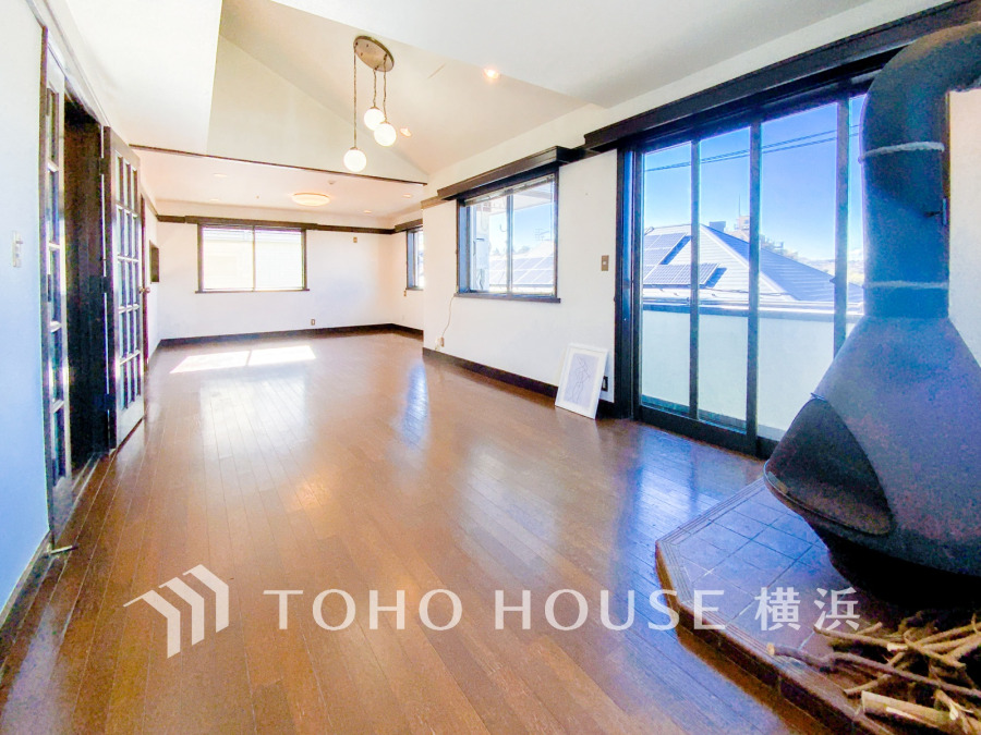 大きな窓から光が差し込む開放的なリビング。暖炉が温かみを演出する快適空間です。