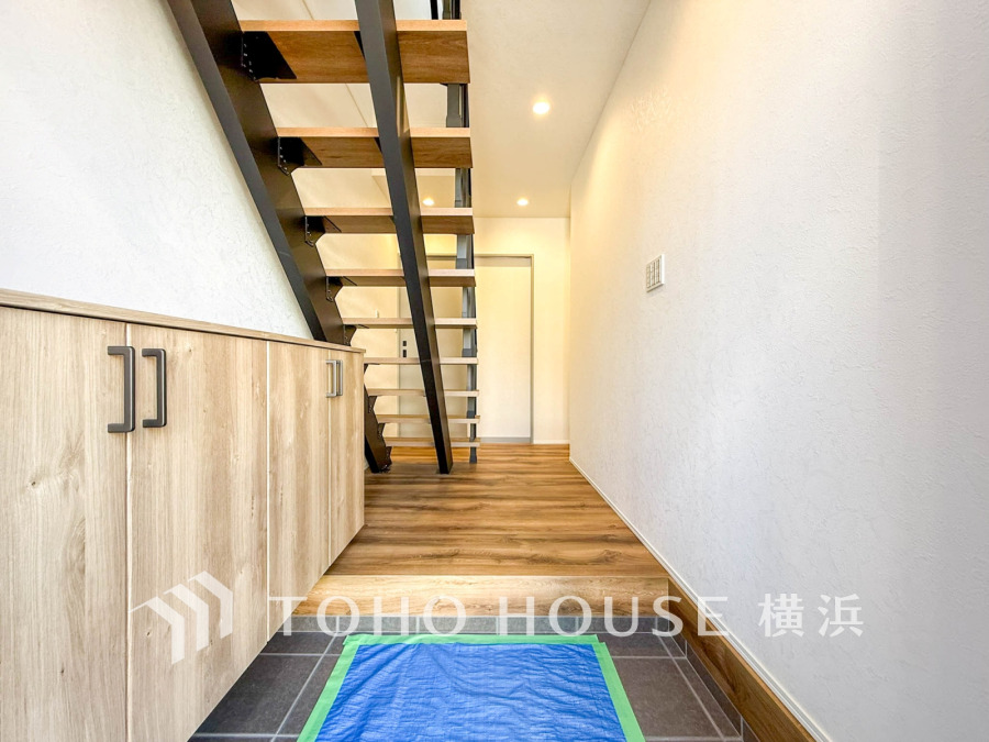 開放感あるスケルトン階段と木目調の収納が魅力の、明るく広々とした玄関ホールです。