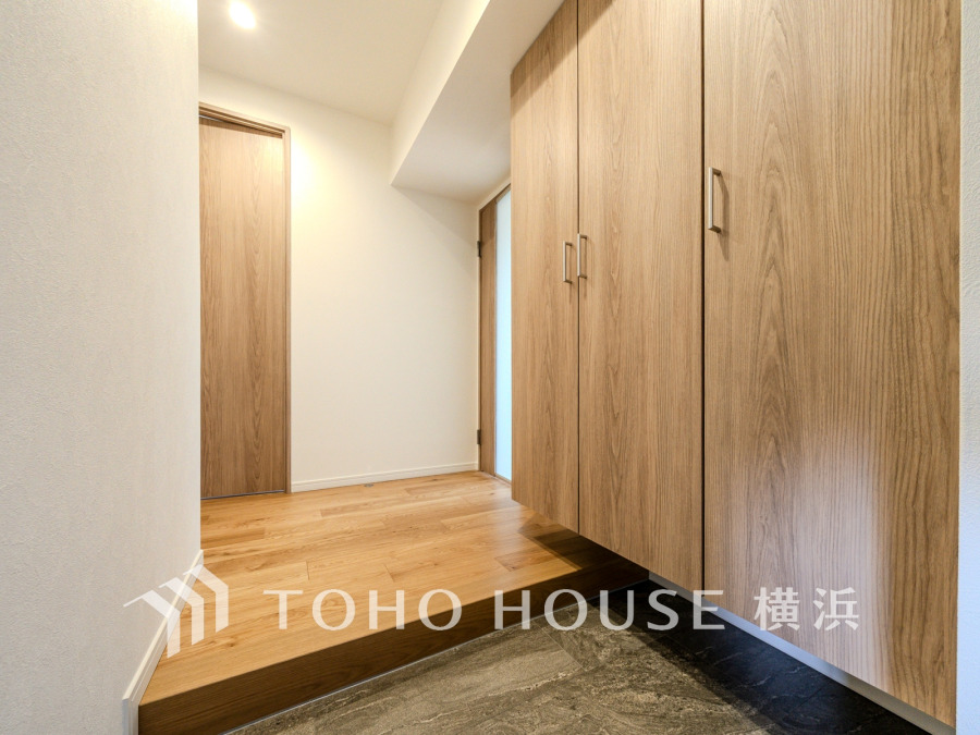 大容量のシューズボックスを備えた玄関。木目調の落ち着いた空間です。