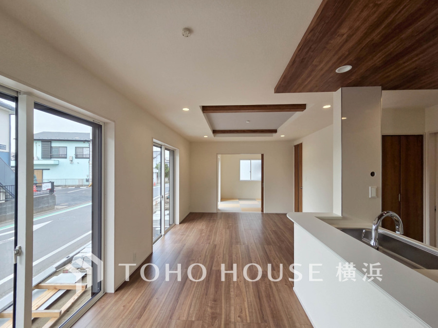 大きな窓から自然光が差し込む、開放感あふれるリビングダイニング。木目調の天井が温かみを演出します。