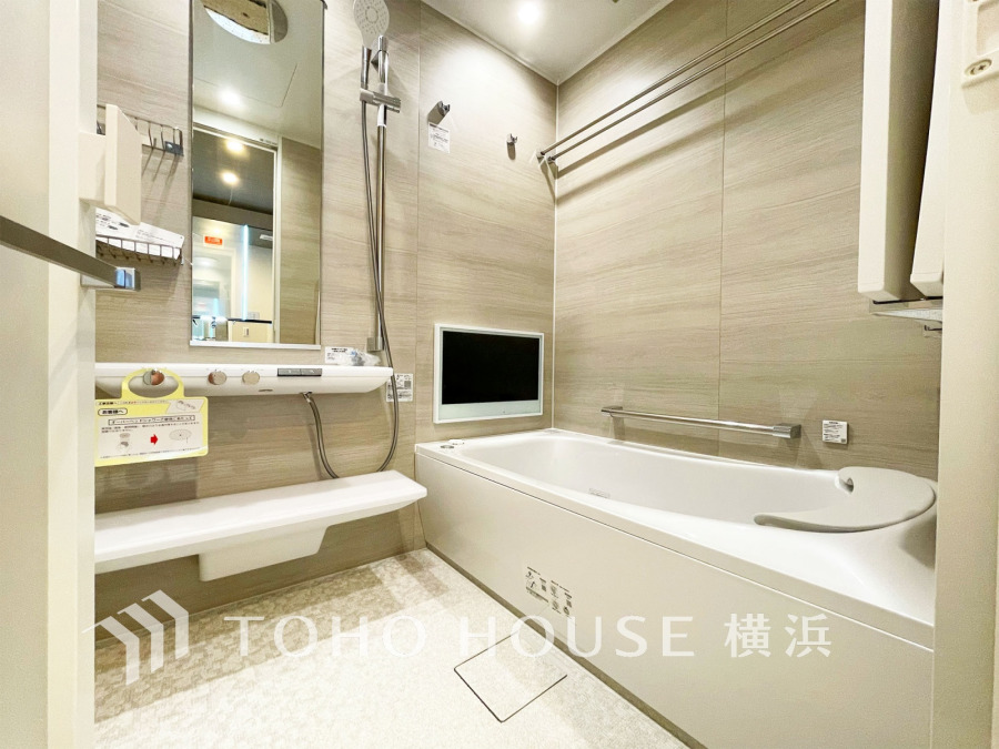 ゆったりくつろげる浴槽と壁掛けテレビを備えた、機能的でモダンなデザインの快適なバスルームです。