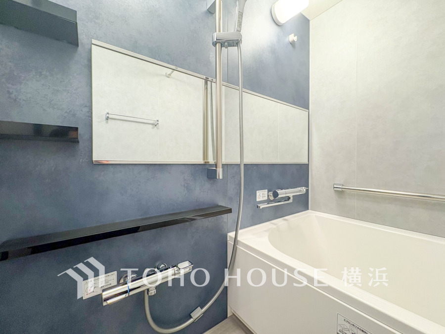 落ち着いたネイビーブルーの壁が印象的な、シンプルで清潔感あふれるバスルームです。