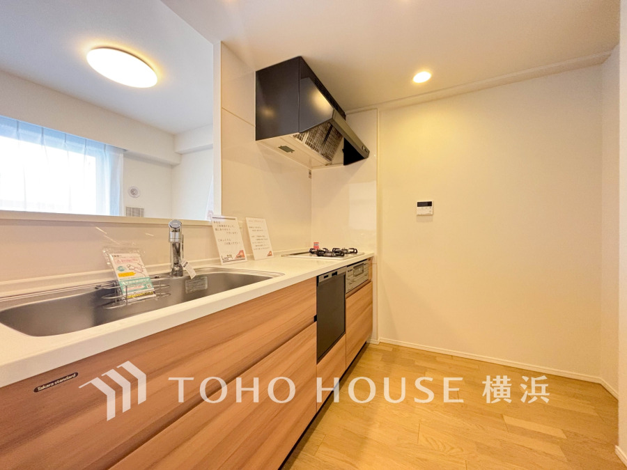 木目調の温かみあるシステムキッチン。対面式でリビングと繋がり、家族との会話も楽しめる快適な空間です。